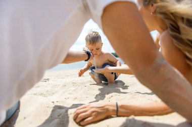 Young family with a toddler resting on the beach. clipart