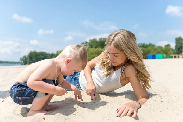 Junge Familie mit Kleinkind ruht sich am Strand aus. — Stockfoto