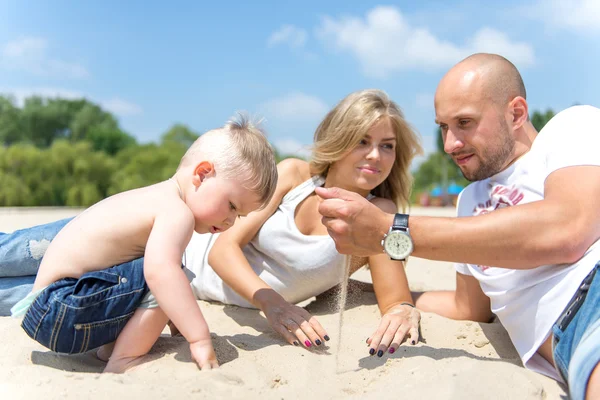 Junge Familie mit Kleinkind ruht sich am Strand aus. — Stockfoto