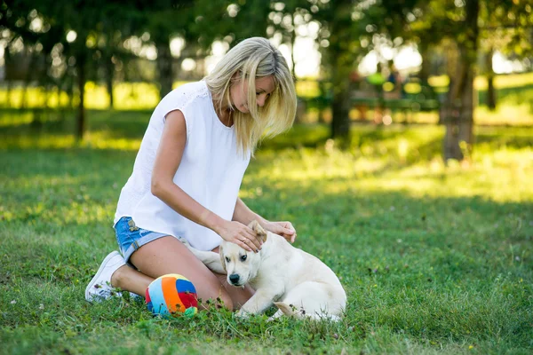 Hermosa chica jugando con un cachorro labrador . — Foto de Stock