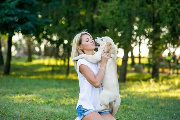 Hermosa chica jugando con un cachorro labrador . — Foto de Stock