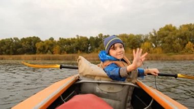 Sonbaharda nehir boyunca akşam kanosu gezisi. Ailedeki çocuğun aktif yaşam tarzı..