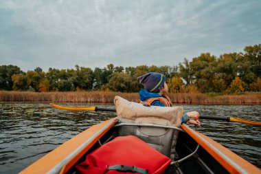 Sonbaharda nehir boyunca akşam kanosu gezisi. Ailedeki çocuğun aktif yaşam tarzı..