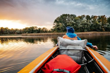 Sonbaharda nehir boyunca akşam kanosu gezisi. Ailedeki çocuğun aktif yaşam tarzı..