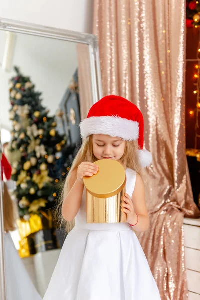 Cute little blonde girl opens a Christmas present. Happy Christmas baby. — Stock Photo, Image