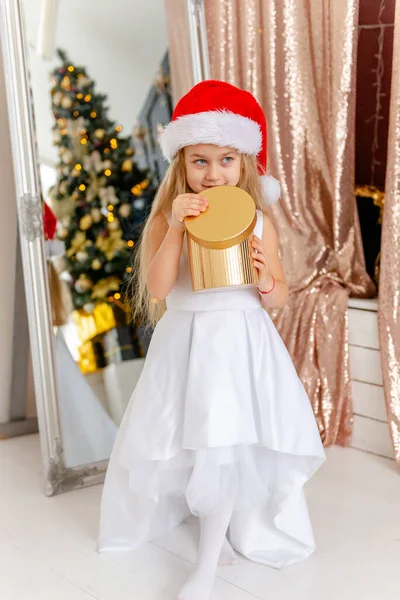 Cute little blonde girl opens a Christmas present. Happy Christmas baby. — Stock Photo, Image