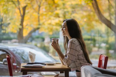 Müslümanların Avrupa 'ya entegrasyonu. Genç ve güzel Müslüman kız Avrupa kültürünü benimsiyor. Genç Müslüman bir kadın kafeteryada tesettürsüz oturuyor..