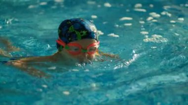 Geleceğin şampiyonu. Küçük şampiyon için yüzme eğitimi. Küçük tatlı çocuk havuzda yüzerek sağlığını güçlendiriyor..
