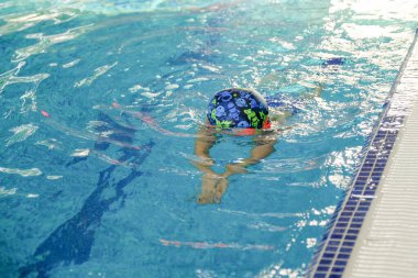 Yeni yürümeye başlayan çocuk havuzda yüzme eğitimi alıyor. Bir çocuk için yüzme eğitimi. Çocuk sporlarının gelişimi. Bebeğin sağlığını güçlendiriyor.
