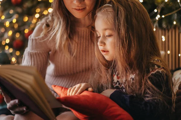 Mother and daughter reading fairytales during Christmas eve, wonderful atmosphere of love and trust, belief in miracles, happy holidays