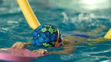 Geleceğin şampiyonu. Küçük şampiyon için yüzme eğitimi. Küçük tatlı çocuk havuzda yüzerek sağlığını güçlendiriyor..