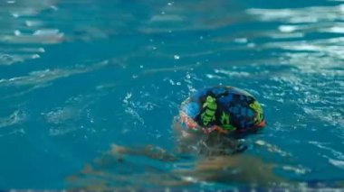 Geleceğin şampiyonu. Küçük şampiyon için yüzme eğitimi. Küçük tatlı çocuk havuzda yüzerek sağlığını güçlendiriyor..