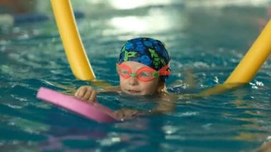 Geleceğin şampiyonu. Küçük şampiyon için yüzme eğitimi. Küçük tatlı çocuk havuzda yüzerek sağlığını güçlendiriyor..