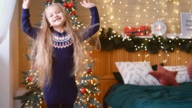 Mutlu Noeller. Çocuk evdeki Noel ağacının yanında neşeyle dans ediyor. Evde mutlu noeller..