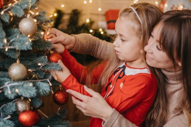 Anne ve kızı Noel ağacını birlikte süsler. Geleneksel ebeveynlik.