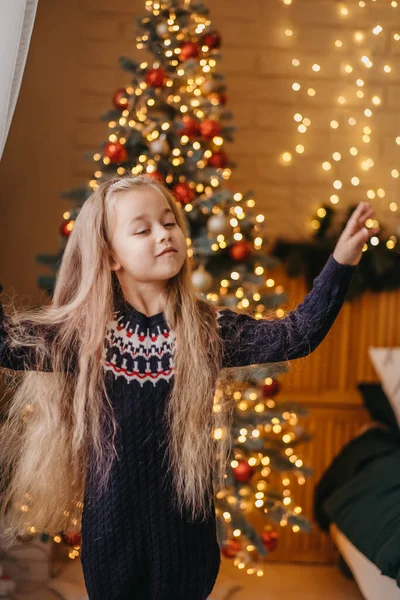 Merry Christmas concept. The child is dancing merrily near the Christmas tree at home. Merry Christmas celebration at home. — Stock Photo, Image