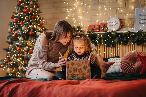 Chica emocionada con madre abre caja de regalo de Santa Claus, infancia feliz, celebración de vacaciones, milagro de Navidad — Foto de Stock