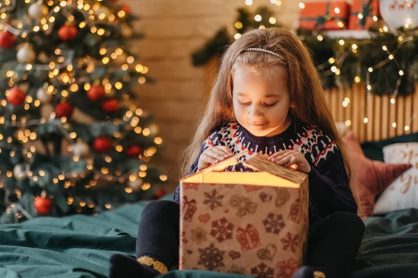 Chica excitada abre caja de regalo de Santa Claus, infancia feliz, celebración de vacaciones, milagro de Navidad — Foto de Stock