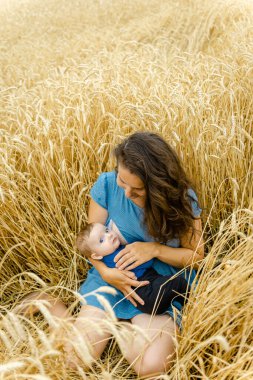 Anne ve bebeği yazın bir buğday tarlasında oturur..