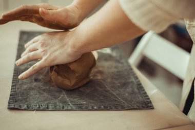 Bir adam elleriyle kil kırıştırır. Çömlek çarkı üzerinde çalış. Usta kil hazırlıyor..