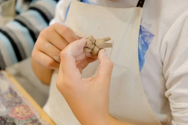 A child molds a product from clay in a modeling lesson.