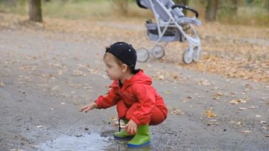 Çocuk yazın yağmurdan sonra parkta bir su birikintisinde oynuyor..
