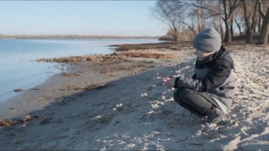 Michigan Gölü kıyılarında yürü. Bir çocuk baharın başında göl kenarında yürür. Nehir kenarında bir çocukla bahar yürüyüşü.