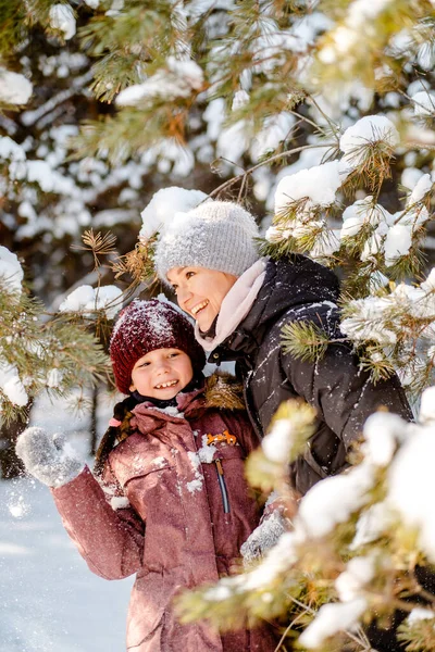 Family winter walk in the forest. Raising a child, family habits. Mother and daughter are having fun in winter in the forest in sunny frosty weather. A mothers hug. — Stock Photo, Image