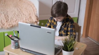 Küçük okul çocuğu evde ders çalışıyor. İnternet üzerinden uzaktan öğrenme. Çocuk öğretmenden bir görev alır ve onunla bilgisayarın web kamerası aracılığıyla iletişim kurar..