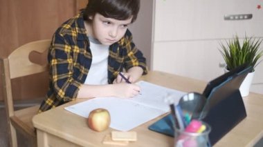 Küçük okul çocuğu evde ders çalışıyor. İnternet üzerinden uzaktan öğrenme. Çocuk öğretmenden bir görev alır ve onunla bilgisayarın web kamerası aracılığıyla iletişim kurar..