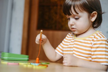 Erken bebek gelişimi. Genç bir otistik çocuğa evde eğitim vermek. Çocuk balık tutmayı öğreniyor..