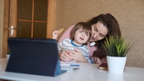 オンライン教育 オンラインで英語を学ぼうとしている小さな子供を持つ若い女性 疲れている若いお母さんはオンライン教育を得ている — ストック動画