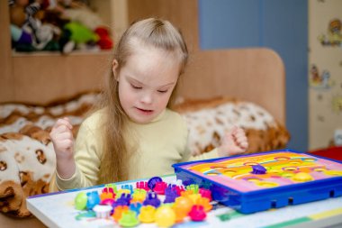 Down sendromlu bir kız COVID-19 Coronavirus salgını sırasında evinde motor becerileri geliştiriyor..