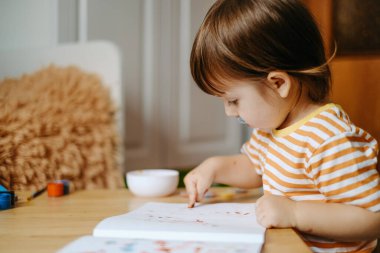 Erken çocuk gelişimi. Çocuğun evde eğitimi. Çocuklara öğretmek için yeni yöntemler ve teknolojiler. Çocukların yaratıcı gelişimi. Çocuk resim yapmayı öğreniyor..