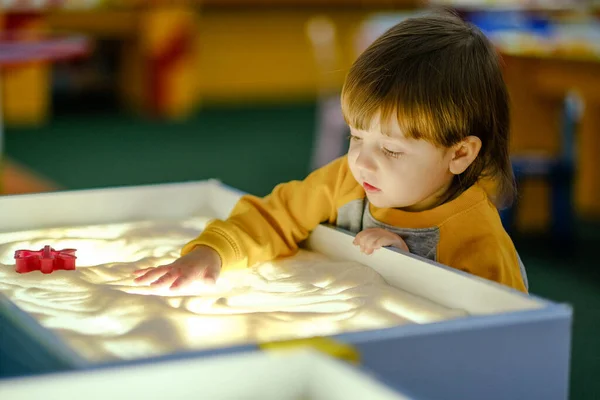 Desarrollo creativo del niño. El bebé dibuja arena sobre vidrio. Desarrollo temprano de los niños. Desarrollo de motilidad superficial y sensaciones táctiles. — Foto de Stock