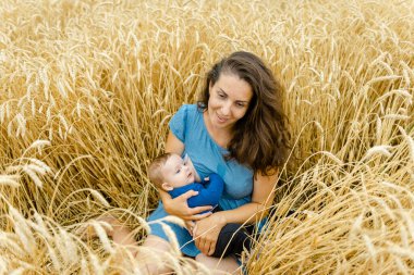 Anne ve bebeği yazın bir buğday tarlasında oturur..