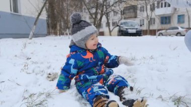 Noel havası. Neşeli ve mutlu çocuk kışın karda oturur. Bebeğinle eğlenceli bir kış yürüyüşü..