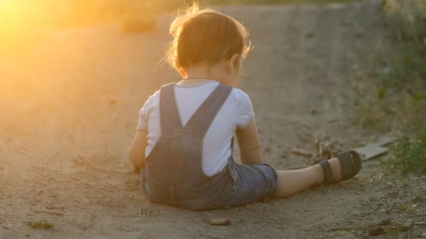 Dzieciak odkrywa otaczający go świat. Szczęśliwego dzieciństwa. Wieczorny spacer z dzieckiem. Dzieciak spotyka się i bada piasek i ziemię w parku.. — Wideo stockowe
