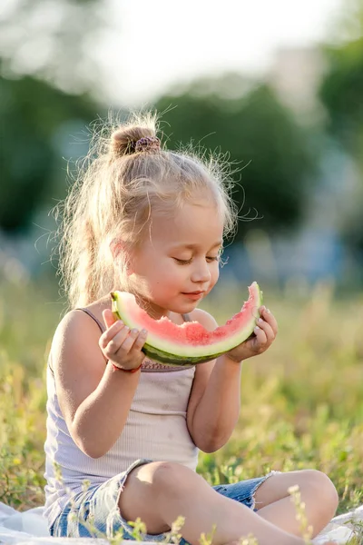 Menina loira comendo melancia no parque. — Fotografia de Stock