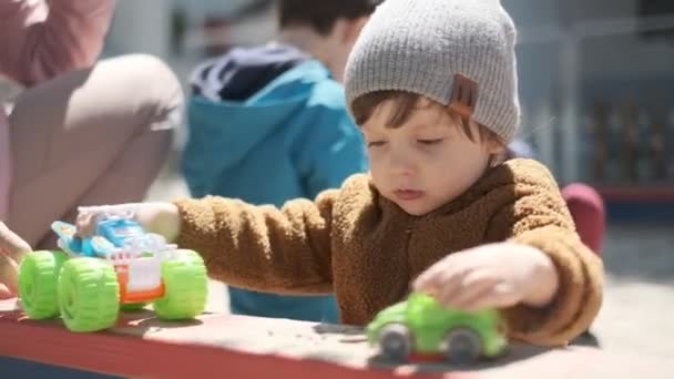 O garoto brinca no playground na primavera. Caminhe com o bebê ao ar livre. — Vídeo de Stock