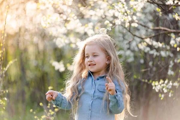 Piccola ragazza bionda che si diverte nel parco primaverile. — Foto Stock