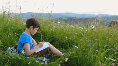 Yazın açık havada çocukların yaratıcı gelişimi. Yaratıcı bir çocuk Alpler 'de bir manzara çiziyor..