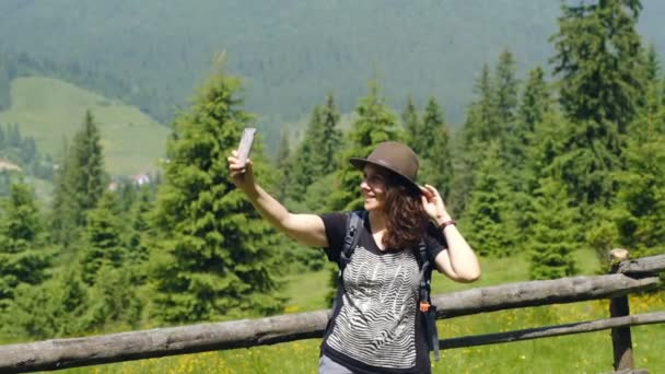 Vandring i bergen i USA. Ung kvinna turist i en vacker hatt gör en selfie i det alpina berget. — Stockvideo