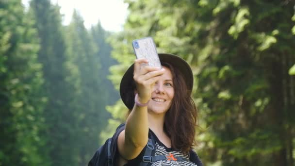 Vandring i bergen i USA. Ung kvinna turist i en vacker hatt gör en selfie i det alpina berget. — Stockvideo