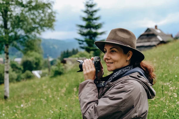 Woman photographer travels in the mountains in summer. Hiking in Europe. A woman photographs alpine landscapes. Travel of the photographer to the mountains.