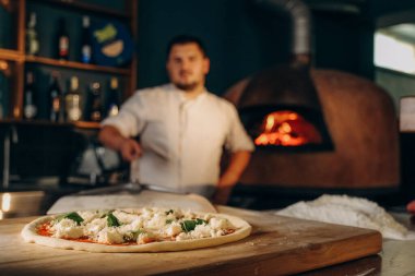Şef ahşap fırında pizza hazırlar. Pizza pişiriyorum. Aşçı pizzayı fırına koyar..