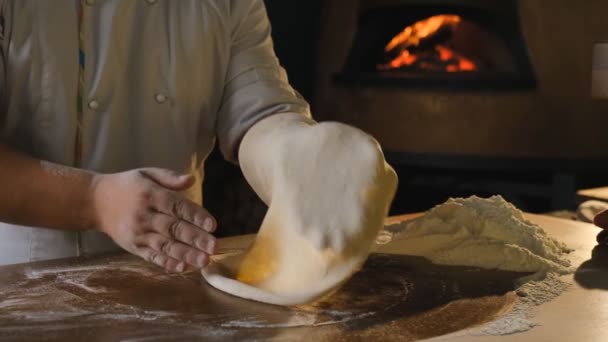 Μαγειρεύω ιταλική πίτσα σε εστιατόριο. Τέντωμα ακατέργαστης ζύμης πίτσα με τα χέρια σας. Ένας επαγγελματίας σεφ τεντώνεται και στρίβει μαλακή ιταλική ζύμη πίτσας με τα χέρια του. — Αρχείο Βίντεο