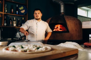 Şef ahşap fırında pizza hazırlar. Pizza pişiriyorum. Aşçı pizzayı fırına koyar. Fırından çıkan lezzetli pizza..