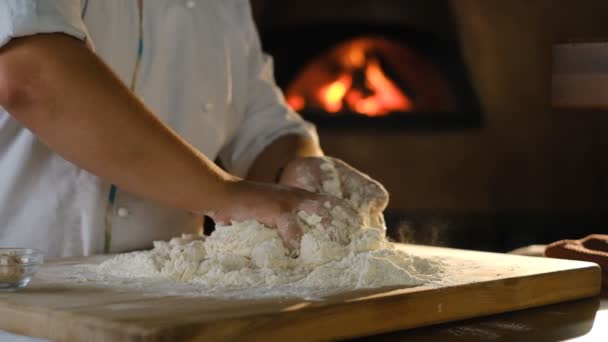 料理人はピザ生地をこねる ピザを作る 男のシェフは ピザのキッチンで木製のテーブルの上に自分の手で生地をこねます — ストック動画