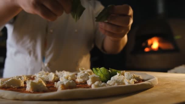 ピザの準備段階 料理はベーキング前にピザにほうれん草の葉を追加します イタリア料理店でピザを作る — ストック動画